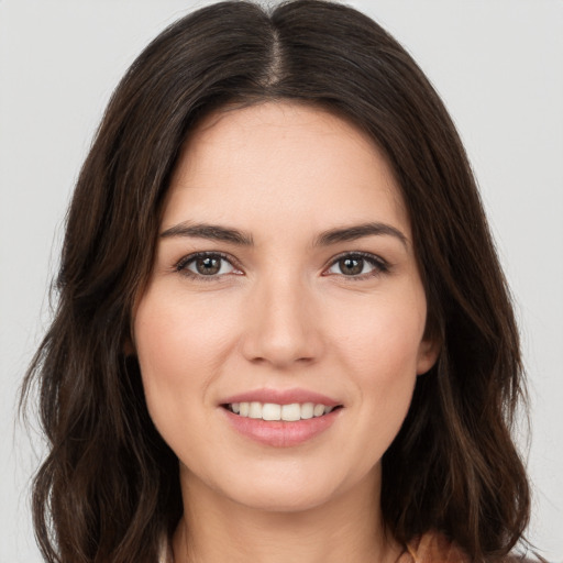 Joyful white young-adult female with long  brown hair and brown eyes