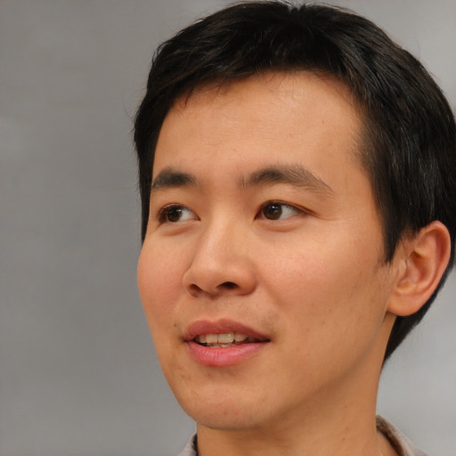 Joyful asian young-adult male with short  brown hair and brown eyes