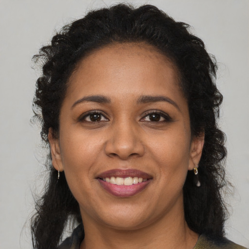 Joyful black young-adult female with long  brown hair and brown eyes