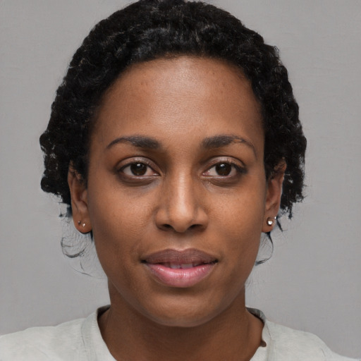 Joyful black young-adult female with short  black hair and brown eyes