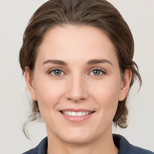 Joyful white young-adult female with medium  brown hair and grey eyes