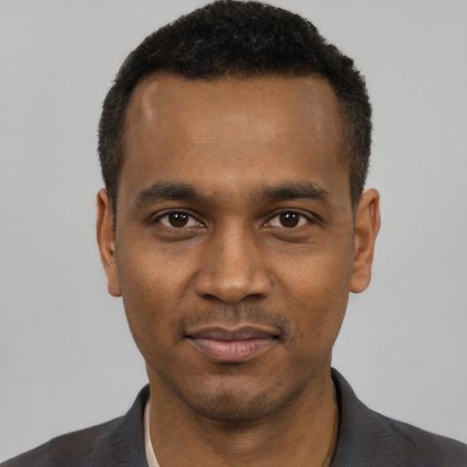 Joyful black young-adult male with short  black hair and brown eyes