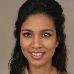 Joyful black young-adult female with long  brown hair and brown eyes