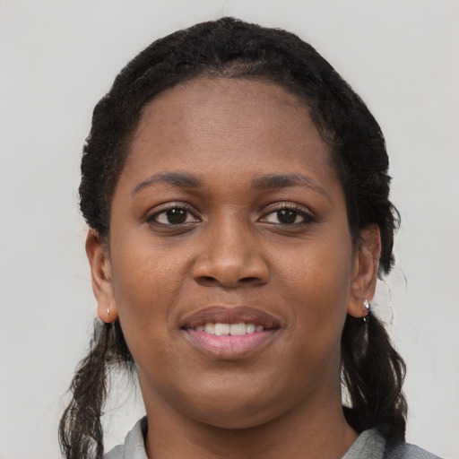 Joyful black young-adult female with long  black hair and brown eyes