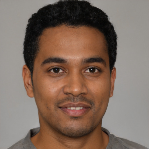 Joyful black young-adult male with short  black hair and brown eyes