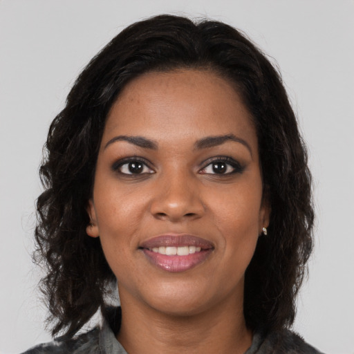 Joyful black young-adult female with long  black hair and brown eyes