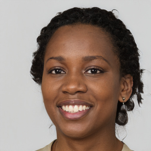 Joyful black young-adult female with long  brown hair and brown eyes