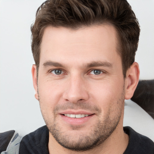 Joyful white young-adult male with short  brown hair and grey eyes