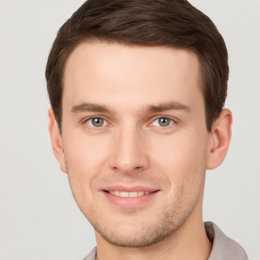 Joyful white young-adult male with short  brown hair and grey eyes