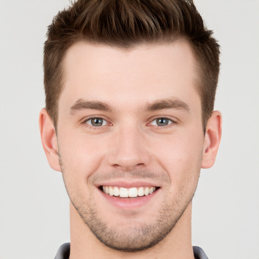 Joyful white young-adult male with short  brown hair and grey eyes