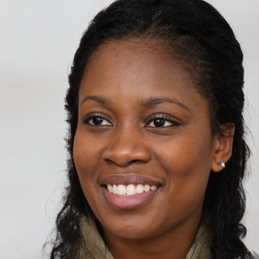 Joyful black young-adult female with long  brown hair and brown eyes