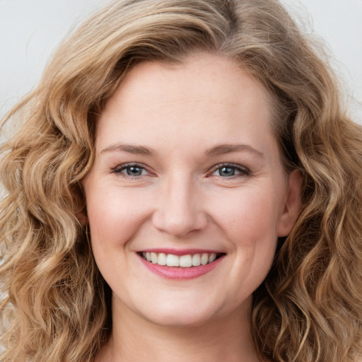 Joyful white young-adult female with long  brown hair and blue eyes