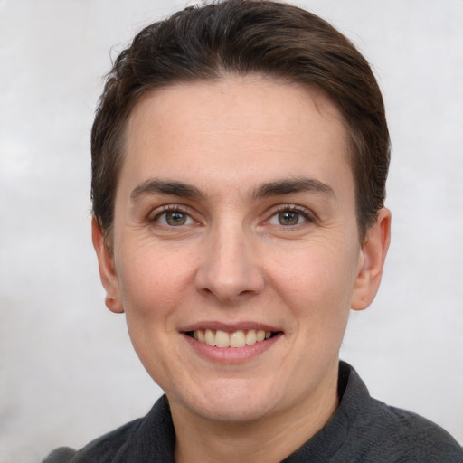 Joyful white young-adult female with short  brown hair and grey eyes