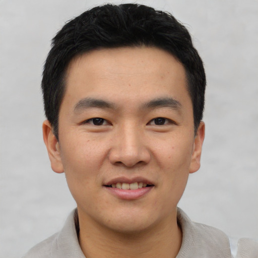 Joyful asian young-adult male with short  black hair and brown eyes