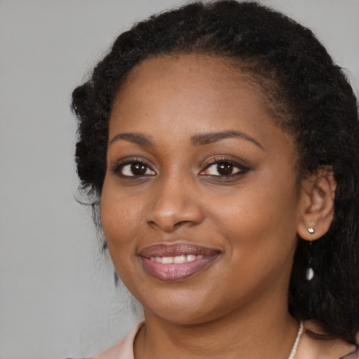 Joyful black young-adult female with long  black hair and brown eyes