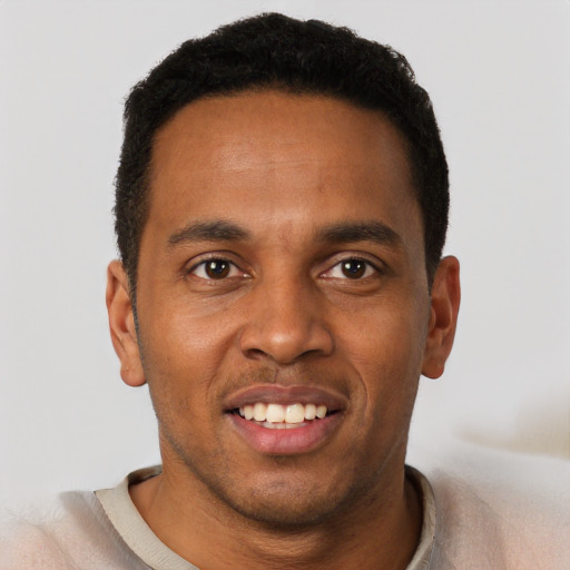 Joyful black young-adult male with short  brown hair and brown eyes