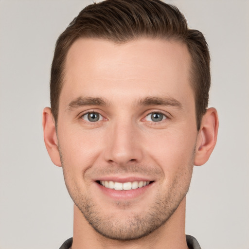 Joyful white young-adult male with short  brown hair and grey eyes