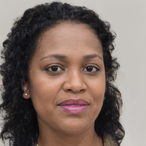 Joyful black young-adult female with long  brown hair and brown eyes