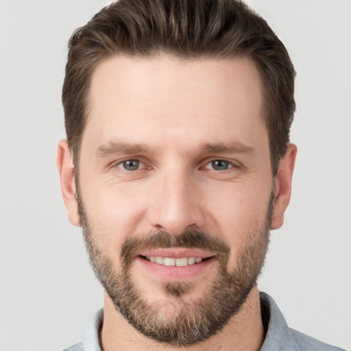 Joyful white young-adult male with short  brown hair and grey eyes