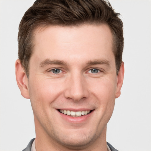 Joyful white young-adult male with short  brown hair and grey eyes