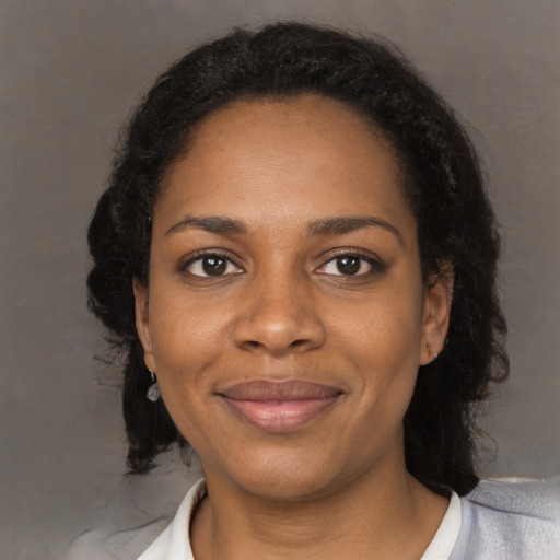 Joyful black young-adult female with long  black hair and brown eyes