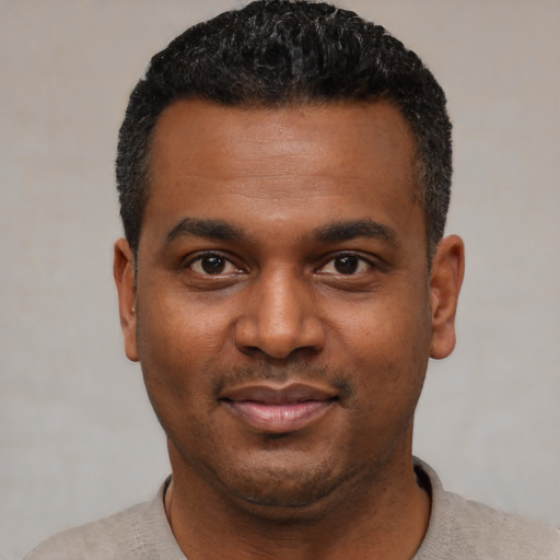 Joyful black young-adult male with short  black hair and brown eyes
