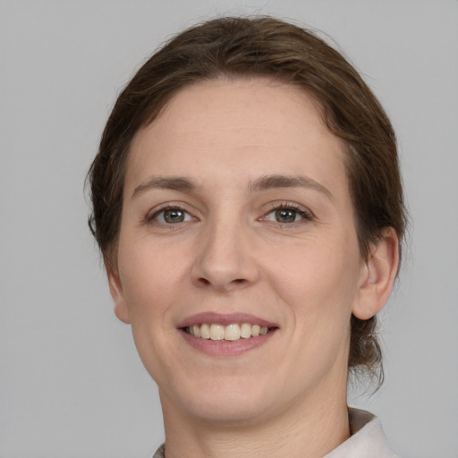 Joyful white young-adult female with medium  brown hair and grey eyes