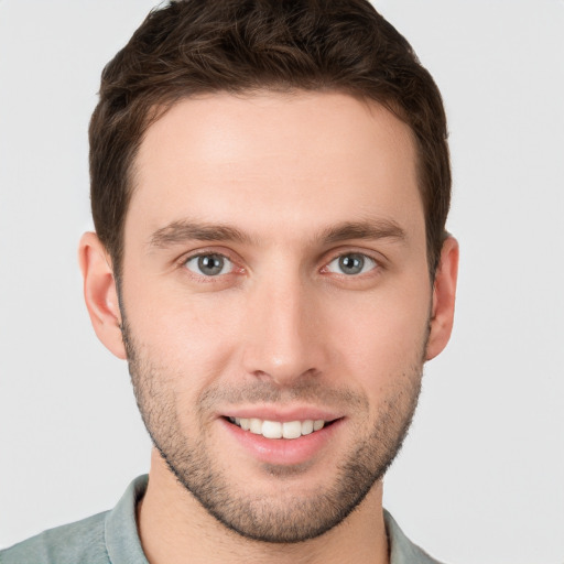 Joyful white young-adult male with short  brown hair and grey eyes