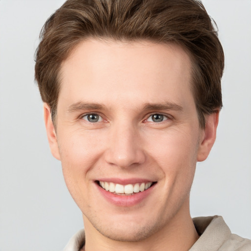 Joyful white young-adult male with short  brown hair and grey eyes