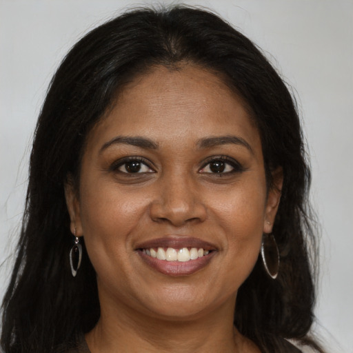 Joyful black young-adult female with long  brown hair and brown eyes