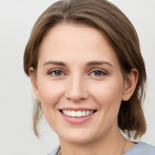 Joyful white young-adult female with medium  brown hair and grey eyes