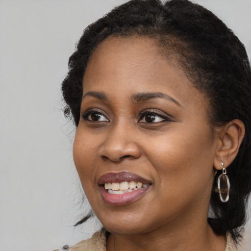 Joyful black young-adult female with long  brown hair and brown eyes