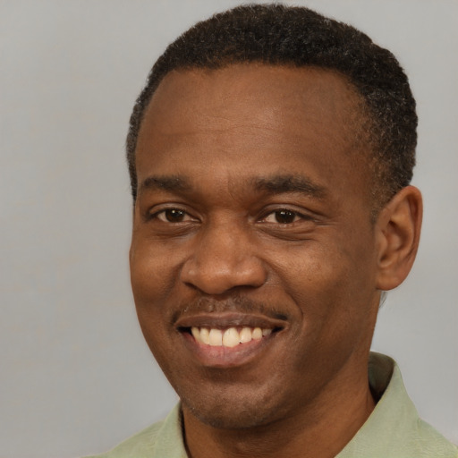 Joyful black young-adult male with short  brown hair and brown eyes