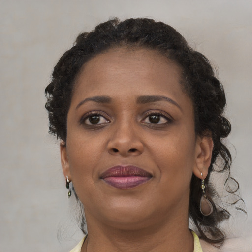 Joyful black young-adult female with long  brown hair and brown eyes