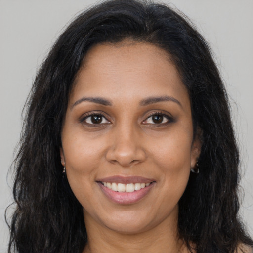 Joyful black young-adult female with long  brown hair and brown eyes