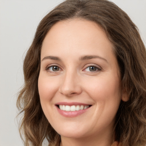 Joyful white young-adult female with long  brown hair and green eyes