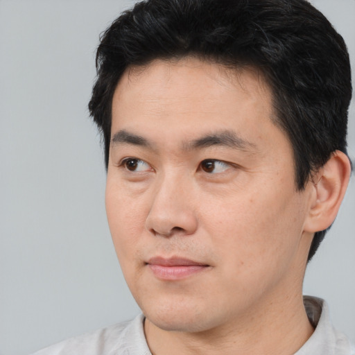 Joyful asian young-adult male with short  black hair and brown eyes