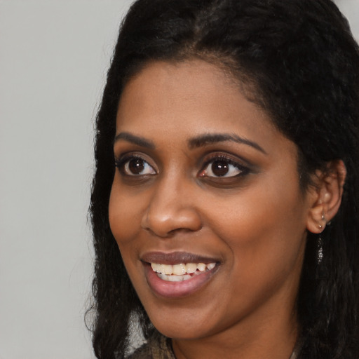 Joyful black young-adult female with long  black hair and brown eyes