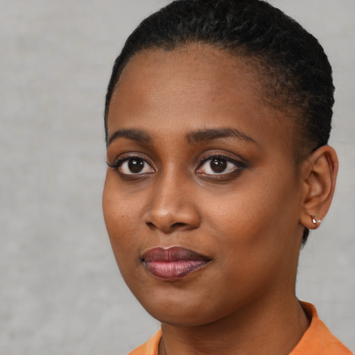 Joyful black young-adult female with short  black hair and brown eyes