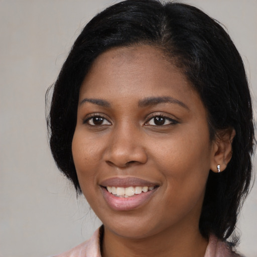 Joyful black young-adult female with medium  black hair and brown eyes