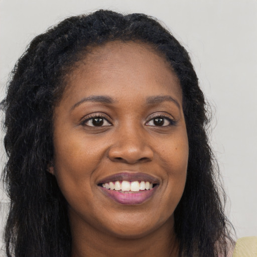 Joyful black young-adult female with long  black hair and brown eyes