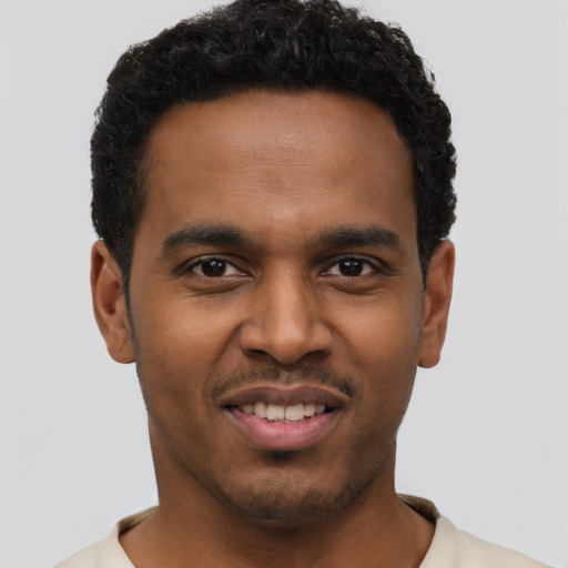 Joyful black young-adult male with short  brown hair and brown eyes