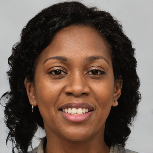 Joyful black adult female with long  brown hair and brown eyes