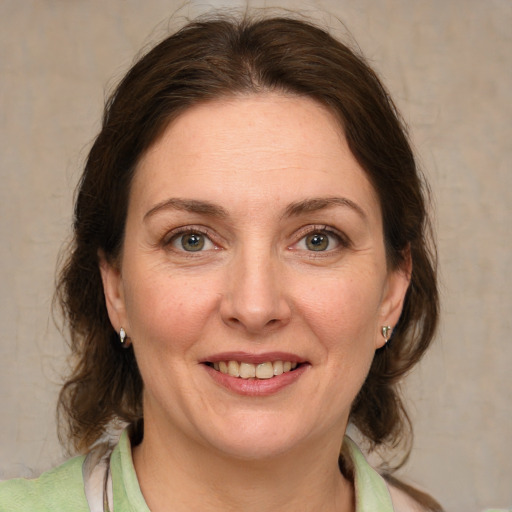 Joyful white adult female with medium  brown hair and green eyes