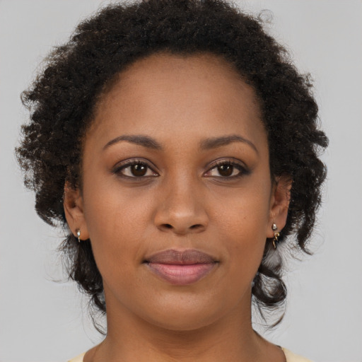 Joyful black young-adult female with long  brown hair and brown eyes