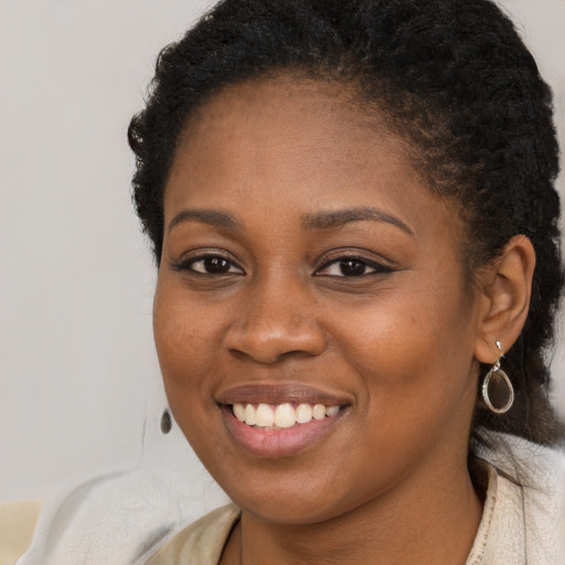 Joyful black young-adult female with long  brown hair and brown eyes