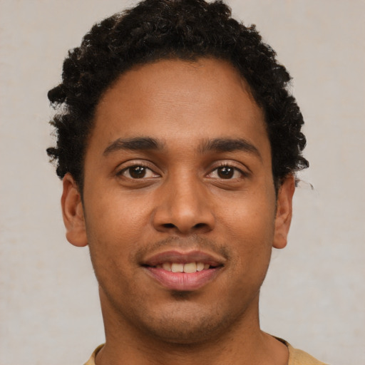 Joyful black young-adult male with short  brown hair and brown eyes