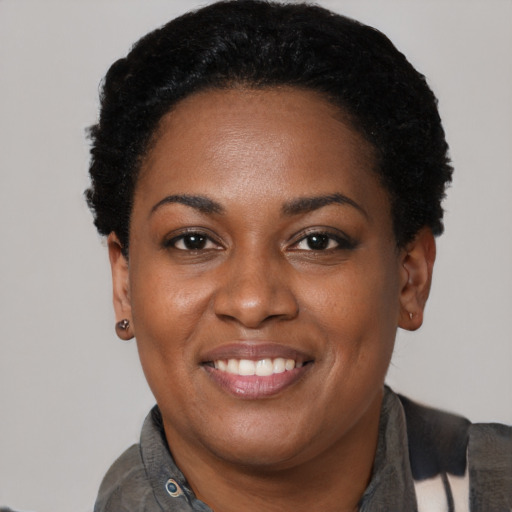 Joyful black young-adult female with short  black hair and brown eyes