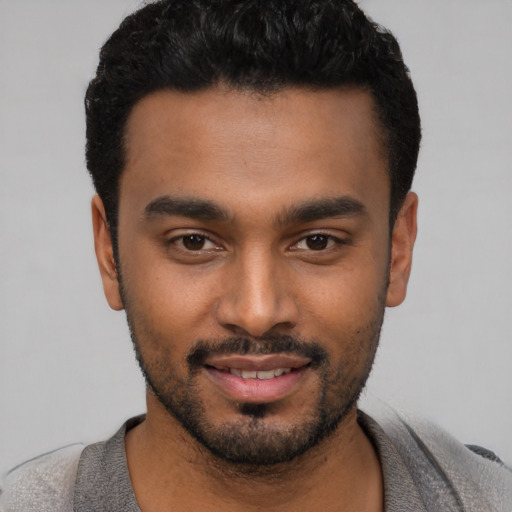 Joyful black young-adult male with short  black hair and brown eyes