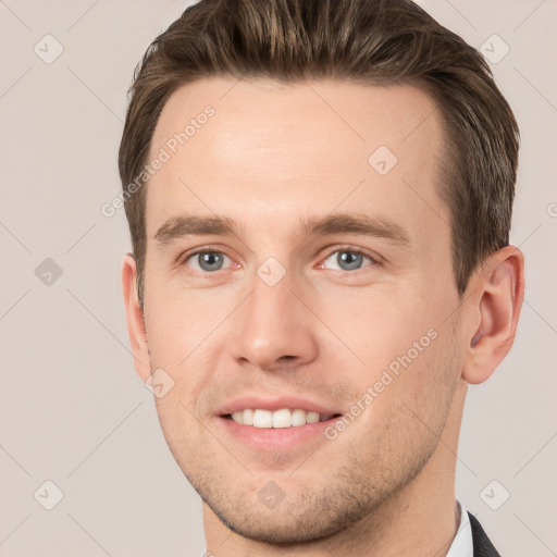 Joyful white young-adult male with short  brown hair and grey eyes